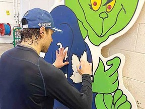 Toronto Maple Leafs star Auston Matthews signs an 2.4-metre Grinch wearing a  Leafs jersey that will be auctioned to raise money for Emmett Gervason to have an operation in California in July. Emmett was born with a congenital ear deformity. His grandfather, who lives in Chatham, came up with idea to make the Grinch and try to get it signed. (Supplied photo)