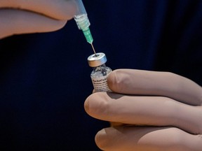 A health-care worker prepares a dose of the Pfizer/BioNTech vaccine at a Woodbine Racetrack pop-up vaccine clinic in Toronto in May. (Carlos Osorio/Reuters)