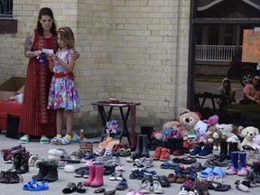 Fae Marshall, 8, and mother Patricia Marshall speak June 4 in Ingersoll at a memorial to students at the former Kamloops Indian Residential School. Fae collected shoes and stuffed animals to pay tribute to 215 Indigenous children who a B.C. First Nation announced last month are believed to be buried in unmarked graves at the former residential school. (Kathleen Saylors/Woodstock Sentinel-Review)