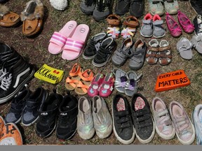 Children's shoes line the base of the defaced Ryerson University statue of Egerton Ryerson, considered an architect of Canada's residential indigenous school system, in Toronto on June 2, following the discovery of the remains of 215 children on the site of British Columbia's former Kamloops Indian Residential School.  REUTERS/Chris Helgren