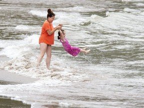 Shawna Ireland swings her daughter, Lily, 4, in and out of the surf at Little Beach in Port Stanley this week. (Derek Ruttan/The London Free Press)