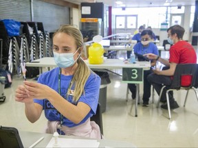 Registered nurse Alex O'Brien was one of several people administering Pfizer vaccines at a pop-up COVID-19 vaccination clinic on June 23, 2021 in the cafeteria of Westminster secondary school in London. (Derek Ruttan/The London Free Press)