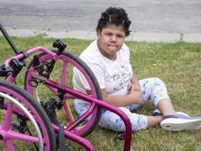 Nine-year-old Aaliyah Faulknor sits beside the remnants of her custom made wheelchair that was stolen and irreparably damaged in London. (Derek Ruttan/The London Free Press)