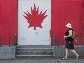 After doing some shopping Catherine Wilson walks past a Canadian flag painted on a boarded-up building on Richmond Street in downtown London on Tuesday. Despite public health restrictions, there are still fun things to do on Canada Day. (Derek Ruttan/The London Free Press)