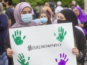 Mariam Boroot, left, and Aya Abdul Hamid, friends of 15-year-old Yumna Afzaal who died when her family was hit by a truck while walking in London in an attack police say was motivated by anti-Muslim hate, hold a sign at a vigil Tuesday for the family at the London Muslim Mosque. Londoners of different faiths are being invited to join a walk Friday night from the crash site on Hyde Park Road to the mosque. (Mike Hensen/The London Free Press)