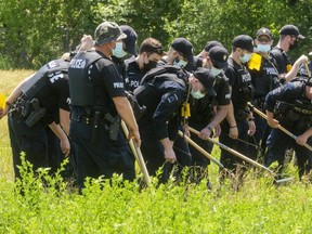 London police officers search for evidence in a grassy lot south of Nelson and Colborne streets. Investigators are probing the suspicious death of a man whose body was found in the area Wednesday. Photo taken Thursday June 10, 2021 (Mike Hensen/The London Free Press)