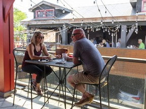 Nicole Flesaru and Scott Burrill of Lucan enjoy lunch Friday, June 11, 2021 on the upstairs patio at Joe Kool's, next door to Toboggan's patio in London, Ont. Flesaru said, "It's wonderful, it feels like we're living again," about being able to dine out at a restaurant, "It's a nice treat."  (Mike Hensen/The London Free Press)
