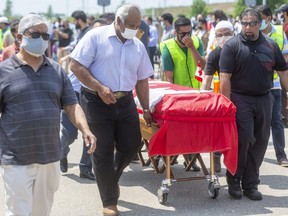 Four Canadian flag-draped coffins for the members of the Afzaal family, killed last Sunday when a vehicle jumped a curb at an intersection and struck them in what police allege was a deliberate attack, are wheeled to the front of a large crowd that gathered Saturday at the Islamic Centre of Southwest Ontario for an outdoor funeral. 
Photograph taken on Saturday June 12, 2021. (Mike Hensen/The London Free Press)