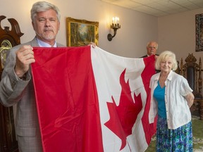 Joe O'Neil, left, and Rob Hardy of O'Neil Funeral Home hold one of four casket flags they had specially made by the Flag Shop for the funeral of four members of the Afzaal family. O'Neil's mother Kate O'Neil, right, suggested draping the caskets with Canadian flags, an honour for those who have been important to their country. (Mike Hensen/The London Free Press)