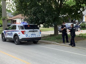 London police officers confer Wednesday as investigators probe the suspicious death of a man whose body was found near Colborne and Nelson streets, in the SoHo area south of downtown, Wednesday. (Norman De Bono/The London Free Press)