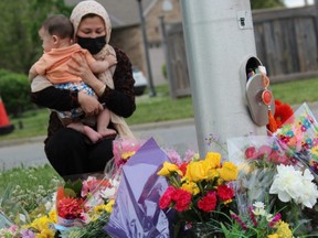 Nafisa Azima holds her son, Seena Safdari, after placing flowers on Hyde Park Road in London where five members of a Muslim family out for a walk were struck by a pickup truck in what London police said was a targeted attack by the driver. Four family members died and the fifth, a nine-year-old boy, was injured. Photo taken June 7, 2021.  (Dale Carruthers, The London Free Press)