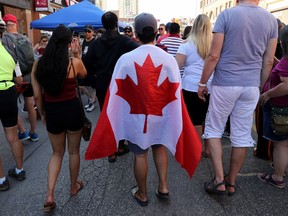 If you are going to put on an extra layer on a hot day it might as well be a flag at the Canada Day Street Festival on Osborne Street in Winnipeg on Mon., July 1, 2019.