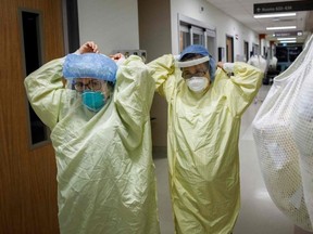 Healthcare workers don personal protective equipment as they prepare to enter the room of a patient suffering from COVID-19 at Humber River Hospital's Intensive Care Unit, in Toronto, Ontario, Canada, on April 29, 2021. (Photo by Cole Burston / AFP)
