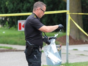 A London police forensic investigator places a blood sample in an evidence bag on Cheapside Street where a woman was seriously injured trying to stop a vehicle theft on Wednesday. Photo taken Wednesday, July 7, 2021. (DALE CARRUTHERS/The London Free Press)