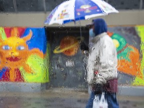 A man is photographed through rain soaked window as he  walks along Dundas Street in London. (Derek Ruttan/The London Free Press)