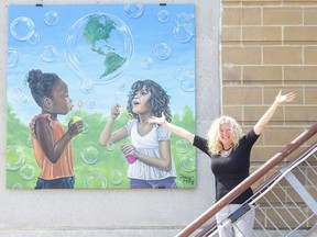 Teresa Marie Phillips, executive director of the Grand Bend Art Centre, celebrates a new set of murals installed on the the Beach House of the Lake Huron community. This painting is by Jorrie Kirby. (Derek Ruttan/The London Free Press)