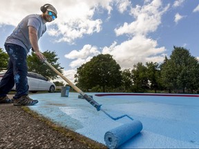 Stan Forster of Tradition Construction rolls another coat of sky blue paint on the McMahen Park wading pool Friday, July 2, 2021. Forster said Tradition had been doing work on several pools and splash pads for the city. Wading pools open Monday. (Mike Hensen/The London Free Press)