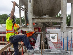 Dillon Needham of Ellis Don controls the flow of concrete out of a bucket as they pour a wall at a tower being built by York Developments at Wonderland Road and Springbank Drive in London on Friday, July 9, 2021. More people joined the regional labour force last month, pushing the unemployment rate to 10 per cent. (Mike Hensen/The London Free Press)
