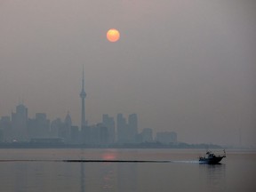 The sun rises through a cover of wildfire smoke above the CN Tower and downtown skyline in Toronto, Ontario, Canada July 20, 2021.