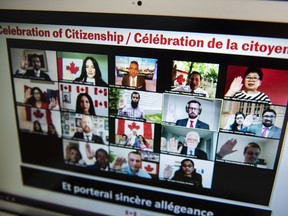 Participants from a variety of backgrounds raise their hands to swear the oath as they become Canadian citizens during a virtual citizenship on July 1, 2020.