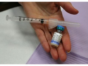 An Ontario public health nurse holds a bottle of the combined vaccine for measles, mumps and rubella. Normally, Ontario students must either receive these vaccinations or complete paperwork opting out of the program. How should we handle the COVID vaccine in schools?