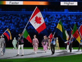 Canada's Damian Warner (L) carries his national flag during the closing ceremony of the Tokyo 2020 Olympic Games, at the Olympic Stadium, in Tokyo, on August 8, 2021. (Photo by Adek BERRY / AFP)