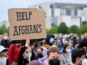 A participant holds up a placard readig 'Help Afghans' during a demonstration near the Chancellery in Berlin on August 17, 2021, to demand the safe passage and airlift out of Afghanistan, where people try flee the country after the Taliban swept back to power. (Photo by JOHN MACDOUGALL/AFP via Getty Images)