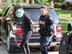 An OPP officer leads a woman to a cruiser outside a townhouse complex near Notre Dame Drive and Viscount Road in London's Westmount area on Monday Aug. 16, 2021. DALE CARRUTHERS / THE LONDON FREE PRESS
