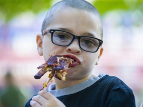 Seven-year-old Damon Dubois digs into lunch during London Ribfest and Craft Beer Festival at Victoria Park in London, on Monday. He was there with his parents Damon Sr. and Starr. "It's really good," he said of his meal. (Derek Ruttan/The London Free Press)