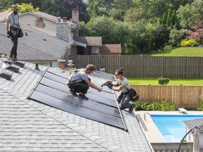 Michael Williams, left, Lyle Lemon and Rachel Hada-Lemon of the solar solutions company Solcan install solar heating panels for a swimming pool in London, Ont. on Friday August 6, 2021. The jobless rate in the London area dropped in July, with the local economy adding 700 jobs. (Derek Ruttan/The London Free Press)