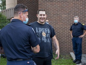 Construction worker Jacob Hurl meets one of his rescuers, London firefighter Stephen Hilton, at No. 3 Fire Station in London on Monday. Hurl was trapped for 4½ hours in rubble at the Nest on Wonderland, an apartment building that partially collapsed Dec. 11, 2020, while under construction. (Derek Ruttan/The London Free Press)