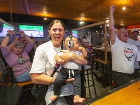 Damian Warner's partner Jen Cotten and their four-month-old son Theo celebrate Warner's run in the 110-metre hurdles in the men's decathlon at the 2020 Tokyo Olympics.  Coaches Dennis Nielsen, seated, and Dave Collins were also in the crowd of 50 of Warner's supporters at the Toboggan Brewing Co. restaurant in London. Photograph taken Weds. Aug 4, 2021. 
Mike Hensen/The London Free Press