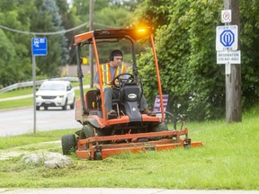 Scott Ferguson of London's parks and recreation department cuts the thick grass along Commissioners Road in Byron. (Mike Hensen/The London Free Press)