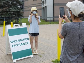 Yoyo Jin, 17, a student at London's A.B. Lucas secondary school, gets her picture taken by Ellen Wang after getting her first COVID-19 vaccination at a pop-up clinic at London's John Paul II high school. (Mike Hensen/The London Free Press)