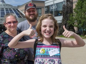 Claire White, 11, is happy after getting her first COVID-19 vaccination at a pop-up clinic at John Paul II secondary school in London. She's with her beaming, fully vaccinated parents Carrie and Danon White. (Mike Hensen/The London Free Press)