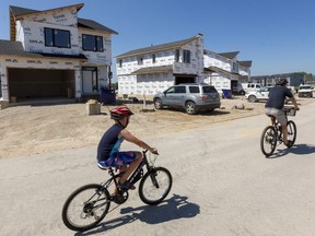 Jay Culbert and his son Oliver, 8, ride through the rapidly growing neighbourhood off of Edgevalley Road, east of Highbury Avenue in London. (Mike Hensen/The London Free Press)