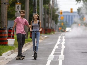 Shailea Davidson, 20 uses her electric scooter named "Uber," to head up the Colborne Street bike paths with her friend Gabriel Ponkin, 21 in tow on his own longboard. (Mike Hensen/The London Free Press)