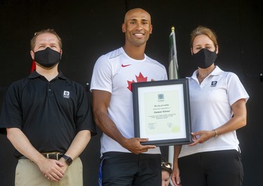 Deputy Mayor Josh Morgan and Coun. Elizabeth Peloza present decathlon gold medallist Damian Warner with a plaque as the city celebrated its Summer Olympics stars in Labatt Park on Saturday August 28, 2021. Mike Hensen/The London Free Press/Postmedia Network