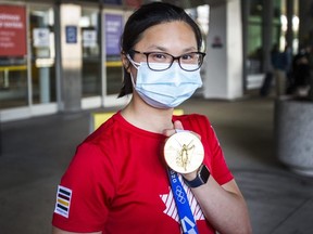 London swimmer Maggie Mac Neil - a three-time Tokyo Olympic medalist with a bronze, silver and gold - shows her gold medal for the 100-metre butterfly after returning to Canada at Pearson International Airport on Monday. (Ernest Doroszuk/Postmedia Network)