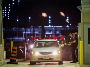 A Canada Border Services Agency Officer hands a traveller their documentation back as other travellers line up behind them to enter Canada after border restrictions were loosened to allow fully vaccinated U.S. residents, after the coronavirus disease (COVID-19) pandemic forced an unprecedented 16-month ban, at the Thousand Islands Bridge crossing in Lansdowne, Ontario, Canada, August 9, 2021.