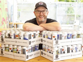 London Brewing Co-op taproom and events manager Tim Stewart with cans of beer that are decorated with work by local artists. (Derek Ruttan/The London Free Press)