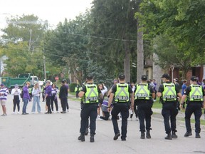 Police officers keep watch on a house party on Broughdale Avenue, near Western University, during Homecoming weekend. (Jonathan Juha/The London Free Press)