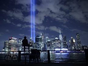 A person watches the Tribute In Light shine into the sky from Lower Manhattan during a test on September 7, 2021 in New York City. Honoring the victims of the September 11, 2001 attack that killed almost 3,000 people at the World Trade Center, the Tribute in Light is a commemorative public art installation that was first presented six months after 9/11 and then every year since on the anniversary. New York City is preparing to mark the 20th anniversary of the September 11 terrorist attacks.  (Photo by Chip Somodevilla/Getty Images)