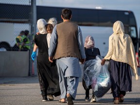 Afghan refugees who supported Canada’s mission in Afghanistan prepare to board buses after arriving at Toronto's Pearson International Airport recently. (Canadian Armed Forces/Reuters)