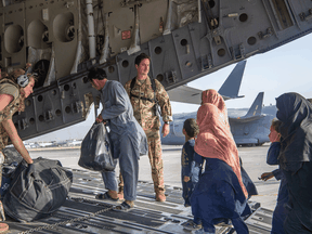 U.S. Air Force members load Afghan passengers aboard a plane as part of evacuation efforts at Hamid Karzai International Airport in Kabul on August 24, 2021.