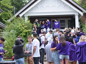 An official stands amid partying students at an off-campus home near Western University during Homecoming weekend. Photo taken Saturday Sept. 25, 2021. Calvi Leon/The London Free Press