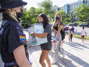 Ioanna Anagnostopoulos of Aurora (left) and Malia Ollen of Stouffville carry belongings to their new home at Western University's Medway-Sydenham Hall student residence  in London on Sunday September 5, 2021. (Derek Ruttan/The London Free Press)