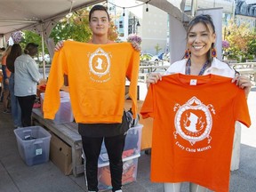 Evan Cabral and Shania Simon were two of many people selling orange shirts at Covent Garden Market as part of an Atlohsa Family Healing Services  campaign. Said campaign co-chair Heather Cabral: "It's about bringing together Indigenous and non-Indigenous people for a common cause, which is love and unity." More than 10,000 shirts have been sold since July. Profits from the sales fund the Atlohsa's Minow Bimaadizwin youth program. (Derek Ruttan/The London Free Press)