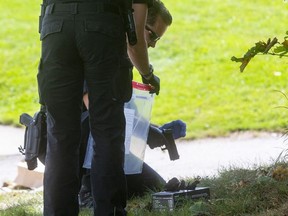 A London police officer prepares to place into an evidence bag what they say was a “semi-automatic pistol” found thrown onto the ground near the entrance to St. Sebastian Catholic elementary school in southeast London. A man was shot nearby and two people were arrested. Photo taken Friday Sept. 10, 2021. (Mike Hensen/The London Free Press)