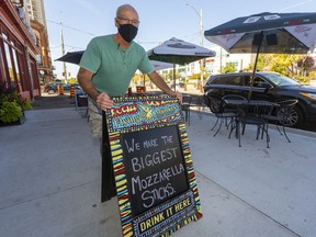 Craig Paulger of J Dee's Market Grill puts out a sidewalk sign on King Street in downtown London on Sept. 26, 2021. Mike Hensen/The London Free Press